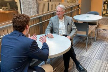 Student Zach Turbin chats with Industry Expert in Residence Duane Schrader at a table in the Goldring/Woldenberg Business Complex