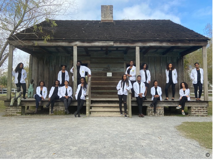 Black medical students stand before a former slave quarters.