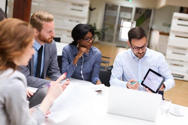 A financial analyst presenting data to co-workers in an office.