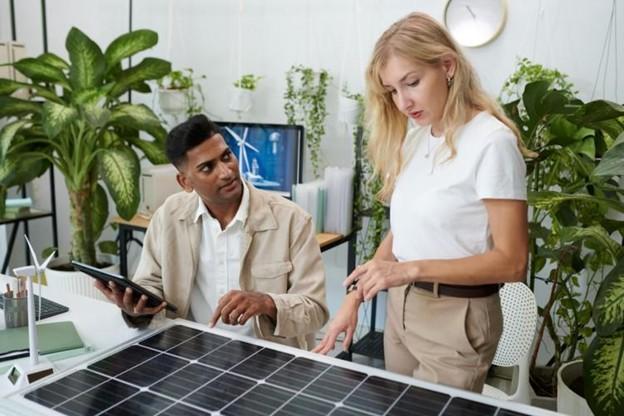 An energy manager examines a solar panel with a coworker.