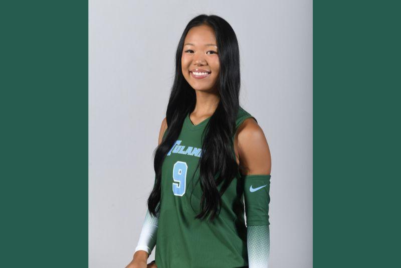 Smiling woman in a green Tulane sports jersey with number 9.