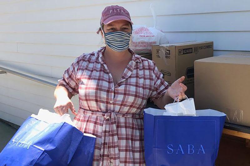 Emily Shaya in facemask with to-go bags.