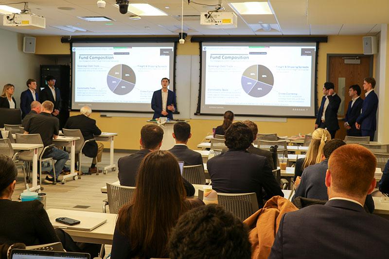 Student in sports coat presents slides at final of Hedge Fund Course