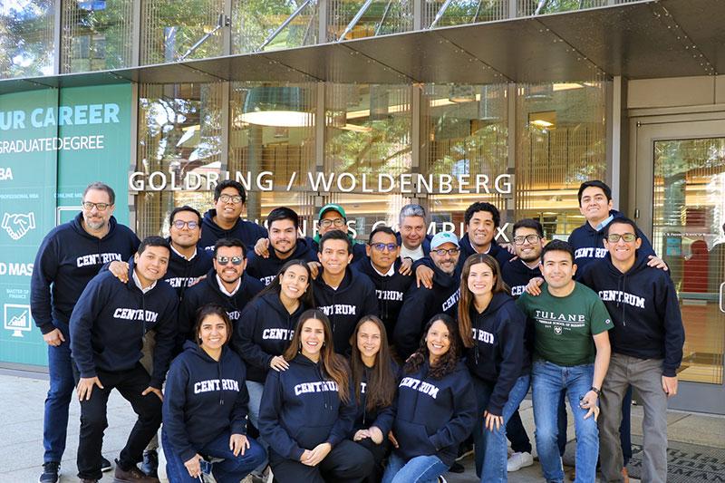 Students wearing CENTRUM sweatshirts pose together, smiling, outside the Goldring/Woldenberg Business Complex