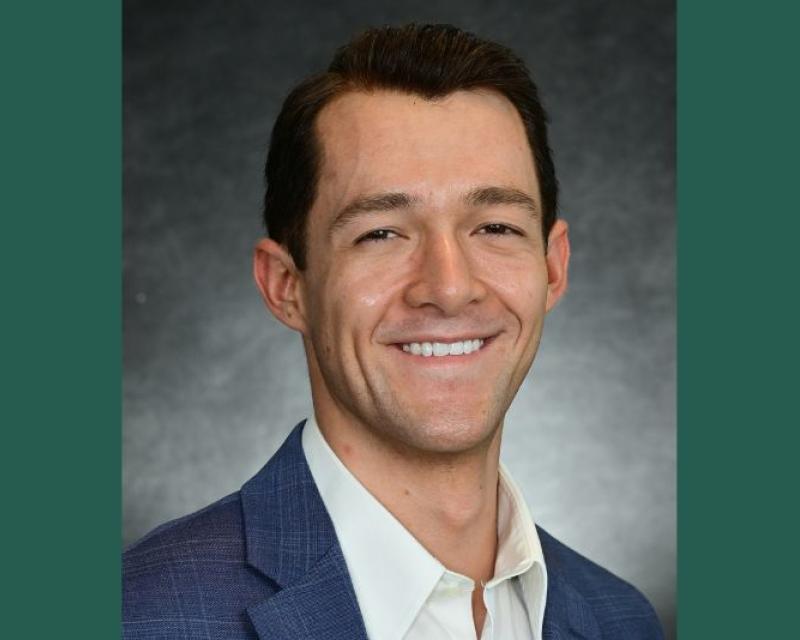 Professional photograph of a smiling man in a blue suit and white shirt.
