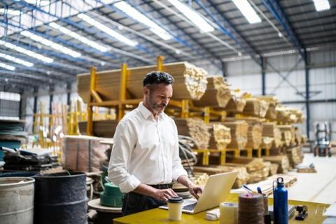 A supply chain analyst works on a computer in a warehouse.