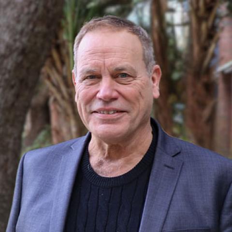 Professional portrait of a smiling man in a dark suit jacket.