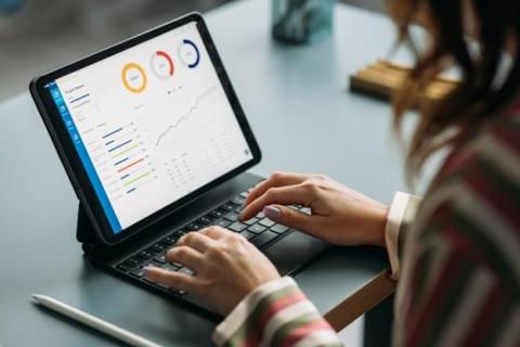 A finance manager working on a laptop reviews a data dashboard.