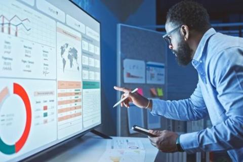 A business analyst reviews a data dashboard on a smartboard