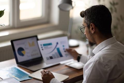 An accountant takes notes while reviewing financial data.
