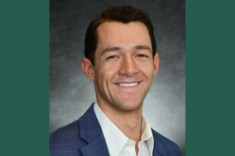 Professional photograph of a smiling man in a blue suit and white shirt.