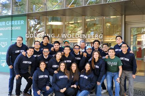 Students wearing CENTRUM sweatshirts pose together, smiling, outside the Goldring/Woldenberg Business Complex