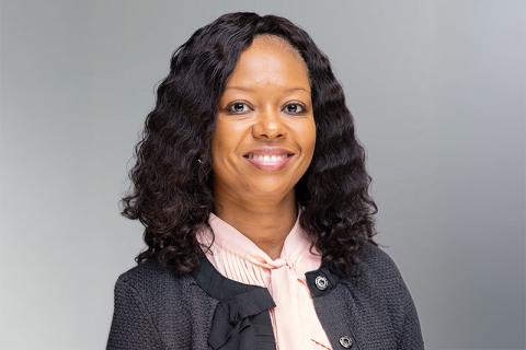 headshot of woman wearing professional attire with a gray background