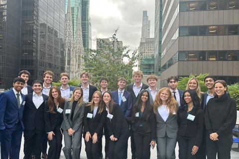 Happy diverse group in business attire posing outdoors with a city skyline.
